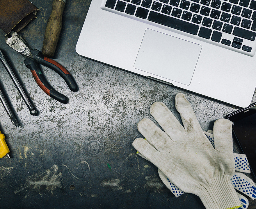 Top view of old tools, laptop and phone on table